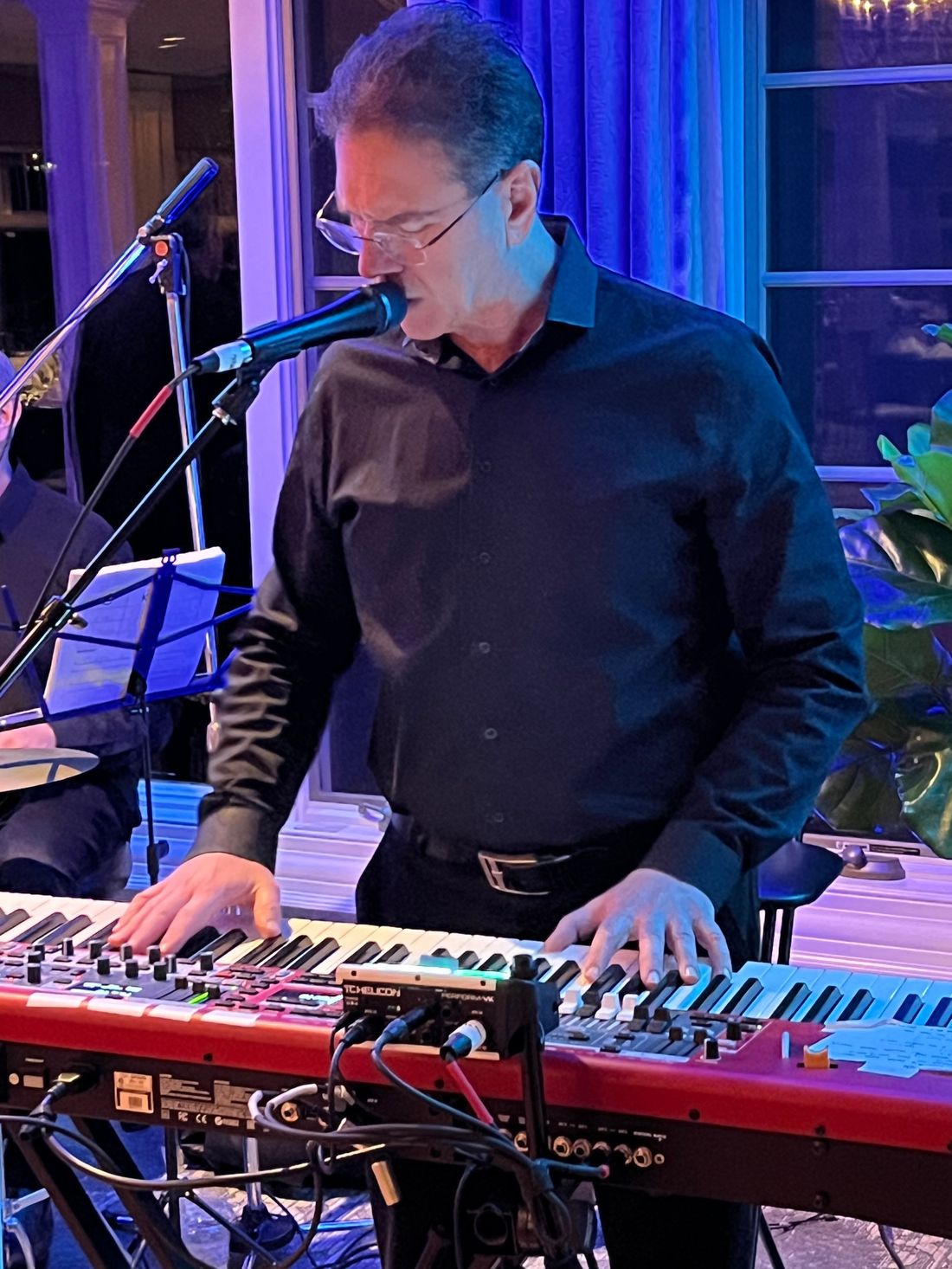 Keyboardist singing into a microphone while playing.