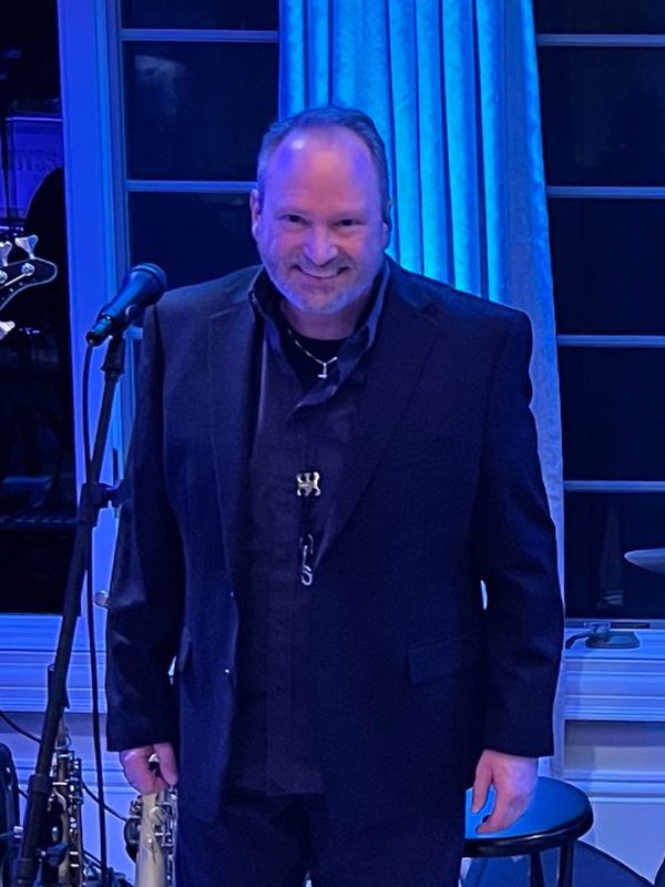 Lead vocalist in a dark suit holding a saxophone.